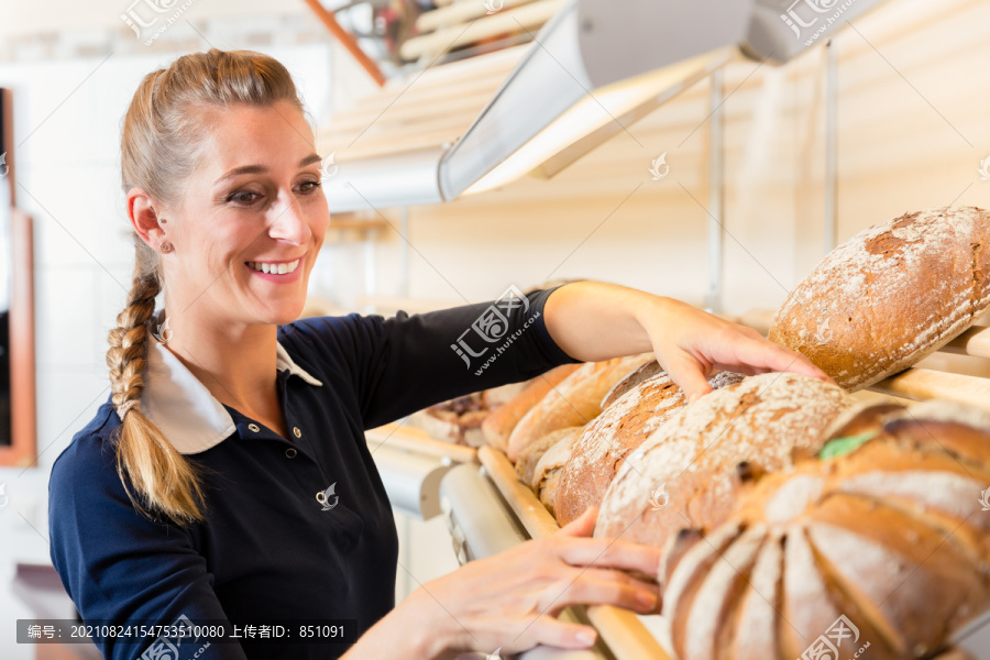 面包店的女人把面包放在商店的架子上卖