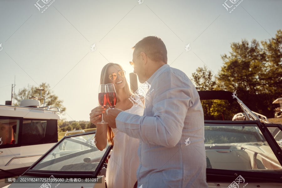 情侣们在河上的船上或游艇上用起泡的酒举杯，背景灯光下的场景