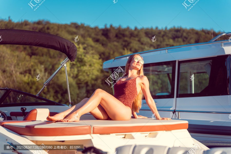 坐在阳光下的河船上晒成棕褐色的女人
