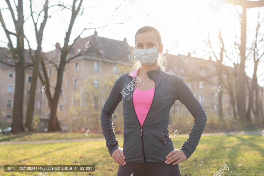 健康危机中的健康女性戴着口罩在草地上户外运动