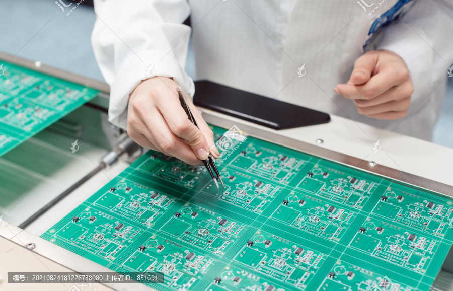 技术人员在生产线上通过将元件插入电路板来组装电子产品
