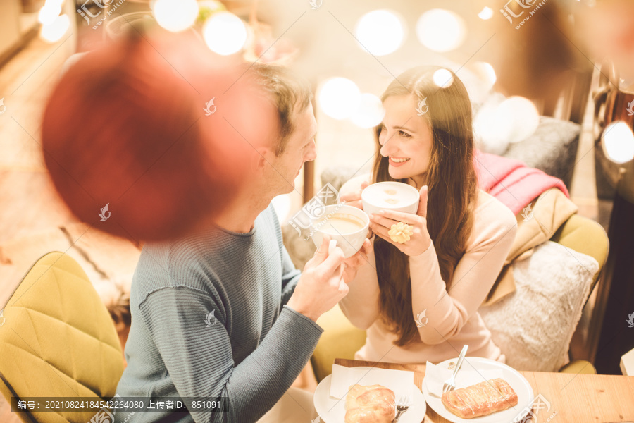 圣诞节期间，一对情侣在咖啡馆里喝着饮料，彼此看着对方