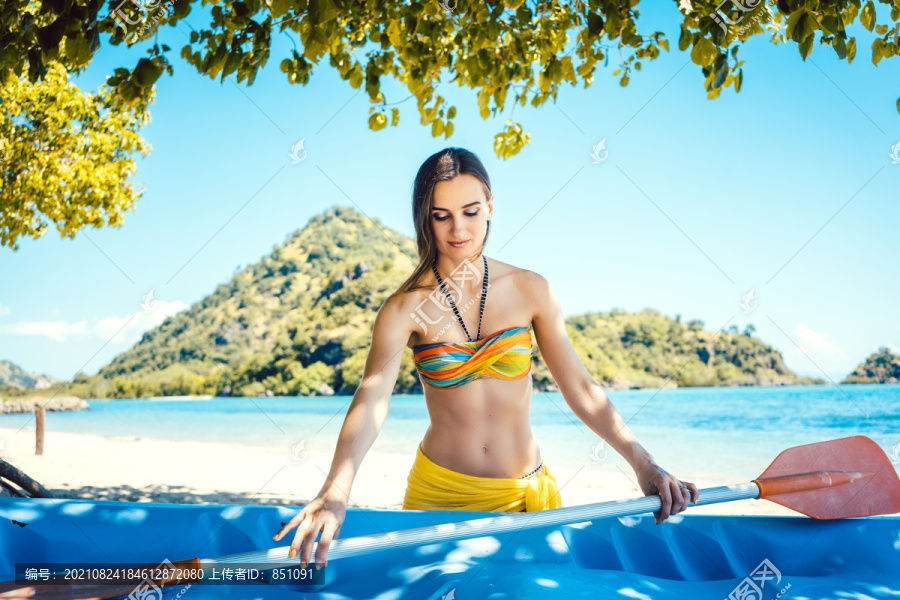 海滩前的一个岛上，穿着比基尼、划着皮艇的女人