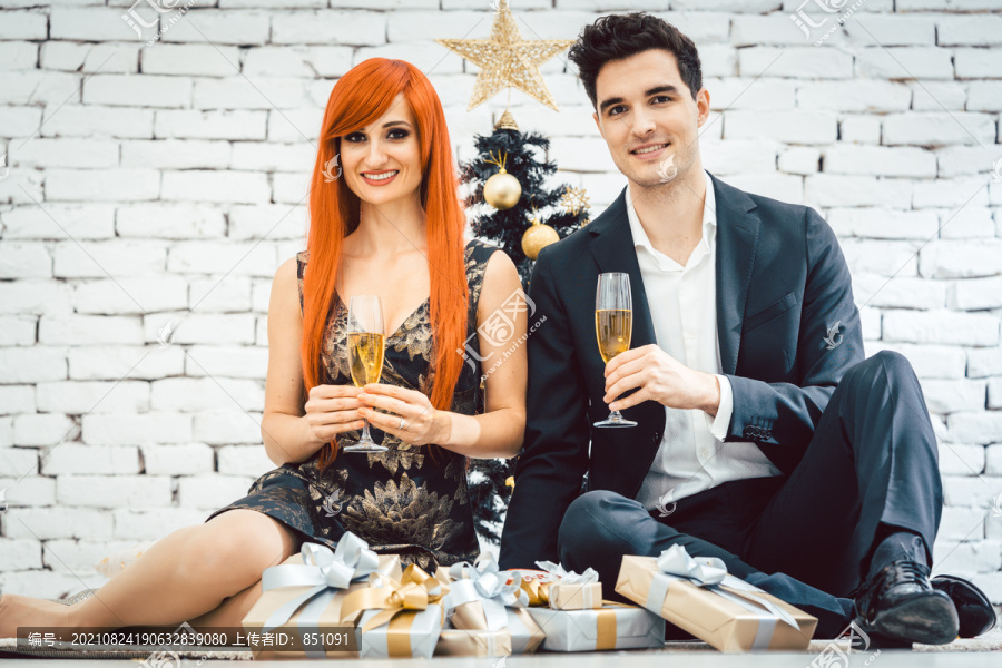 姜黄色头发的女人和男人在黑树前碰杯庆祝圣诞节