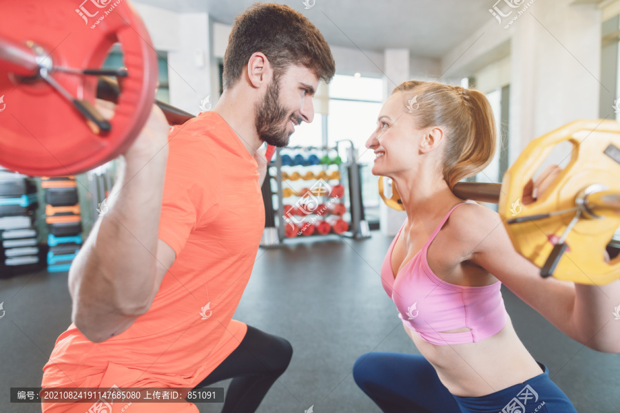 在友谊赛中，一对男女在健身房举重