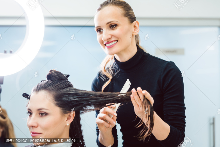 称职的理发师在她的店里为女性理发和定型