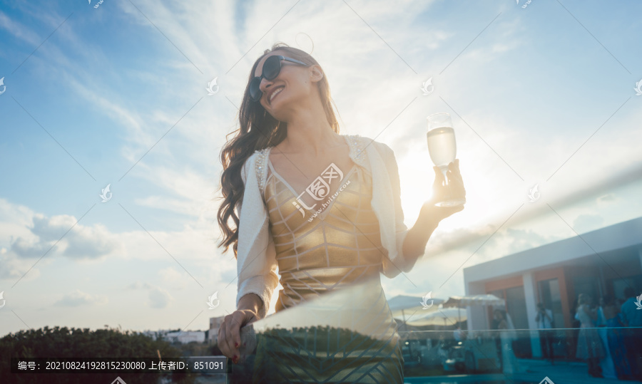 一位女士在夏日派对上喝香槟，背景是维拉