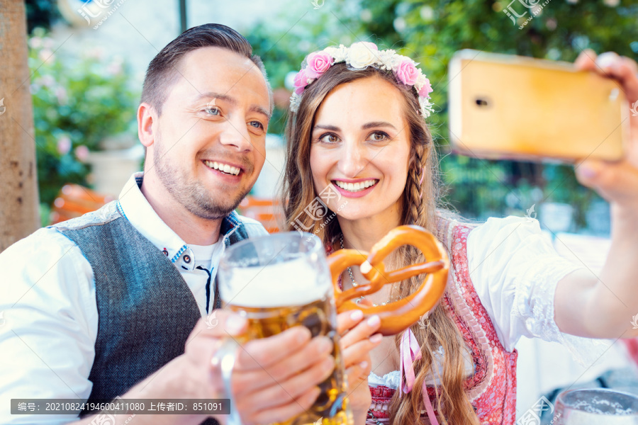 德国啤酒花园里一对快乐的夫妇用手机自拍