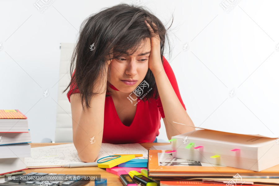 一个沮丧的女孩在学习期间坐在椅子上看书的画像