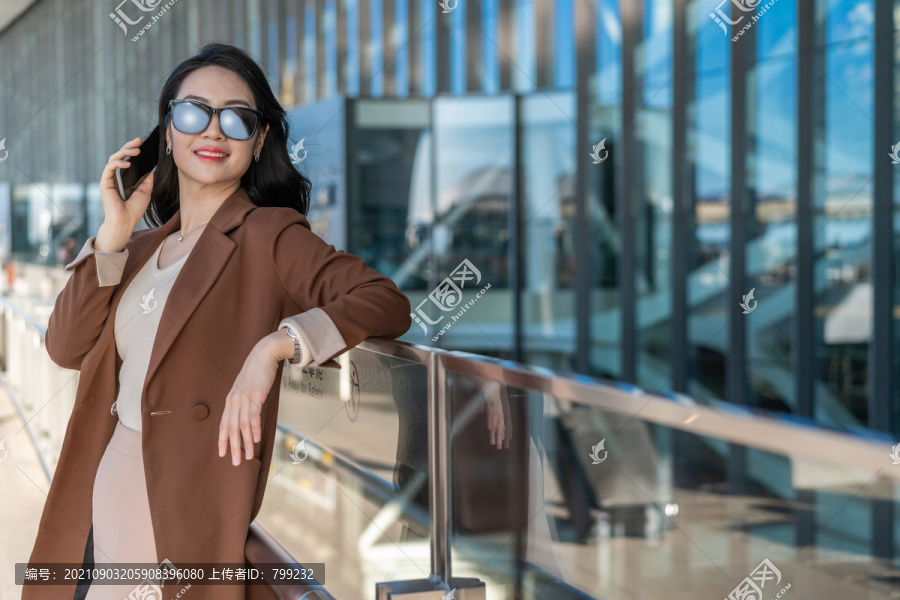 商务女士在机场戴着太阳眼镜打电话