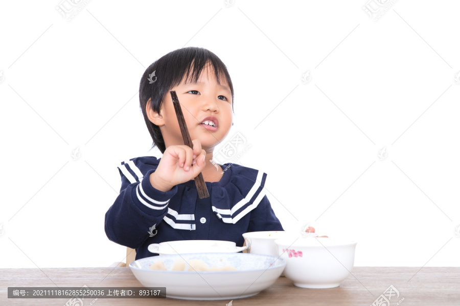 白背景前餐桌旁的小女孩在吃饭