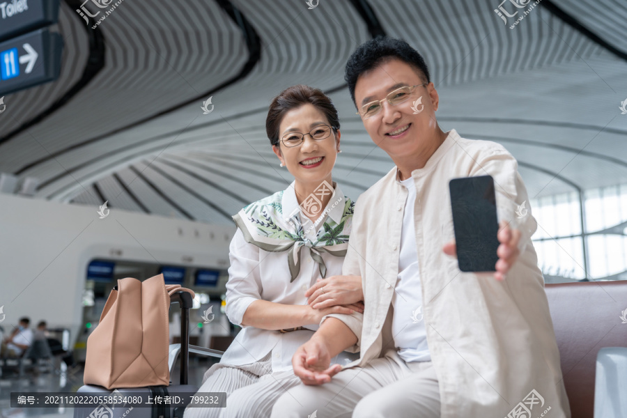 快乐的老年夫妇在机场展示手机