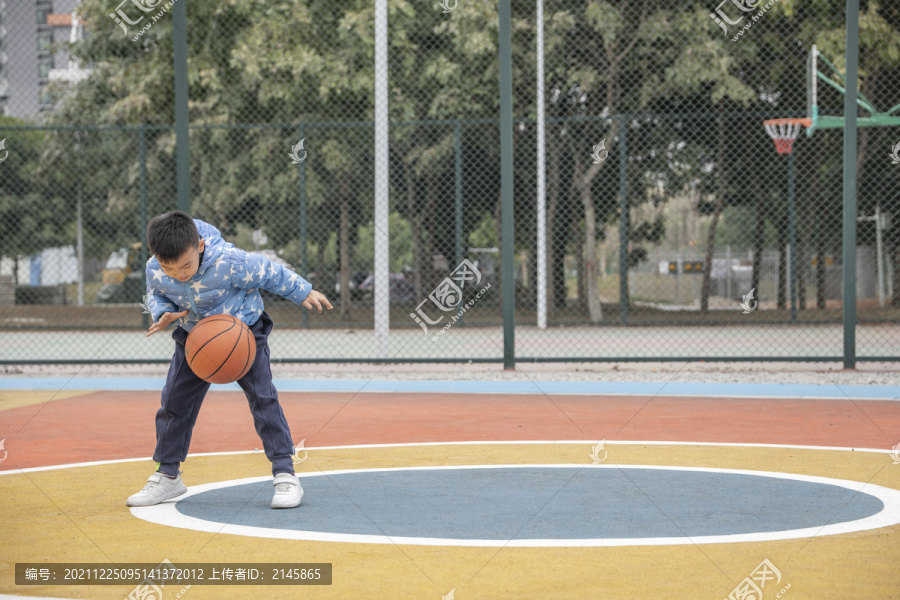 学校操场上打篮球的小男孩