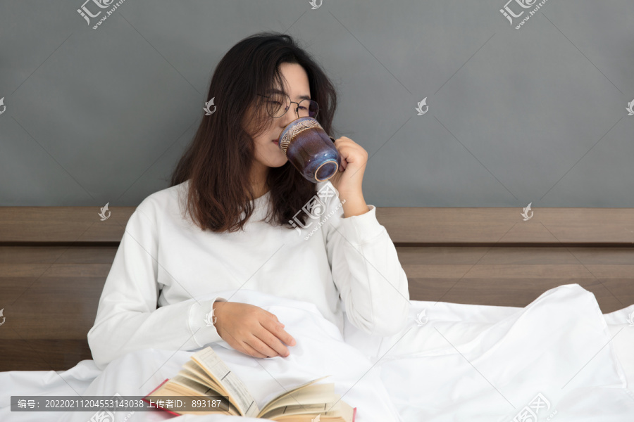 早晨女孩坐在床上喝早茶