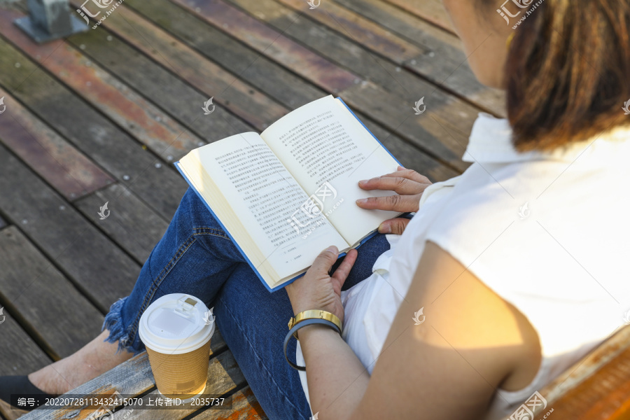 坐在户外长椅看书阅读的女人