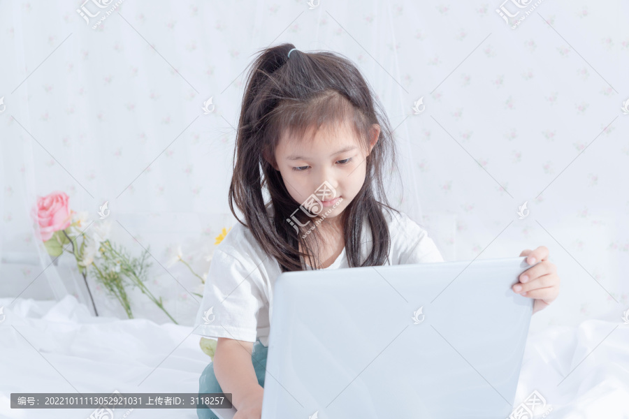 床上使用电脑的小女孩
