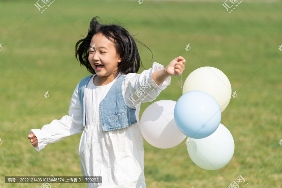 一个小女孩在草地上拿着气球奔跑