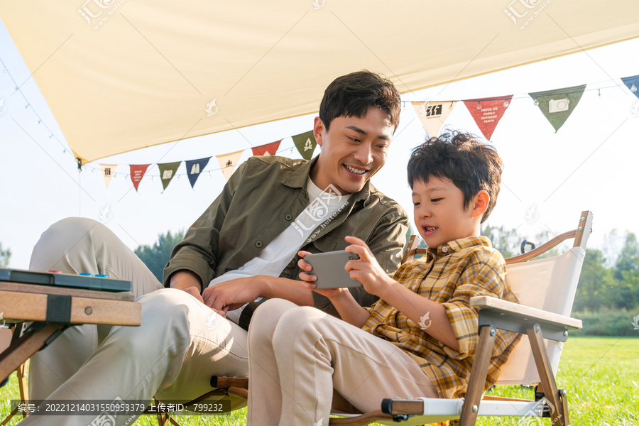 爸爸与儿子在露营地玩手机