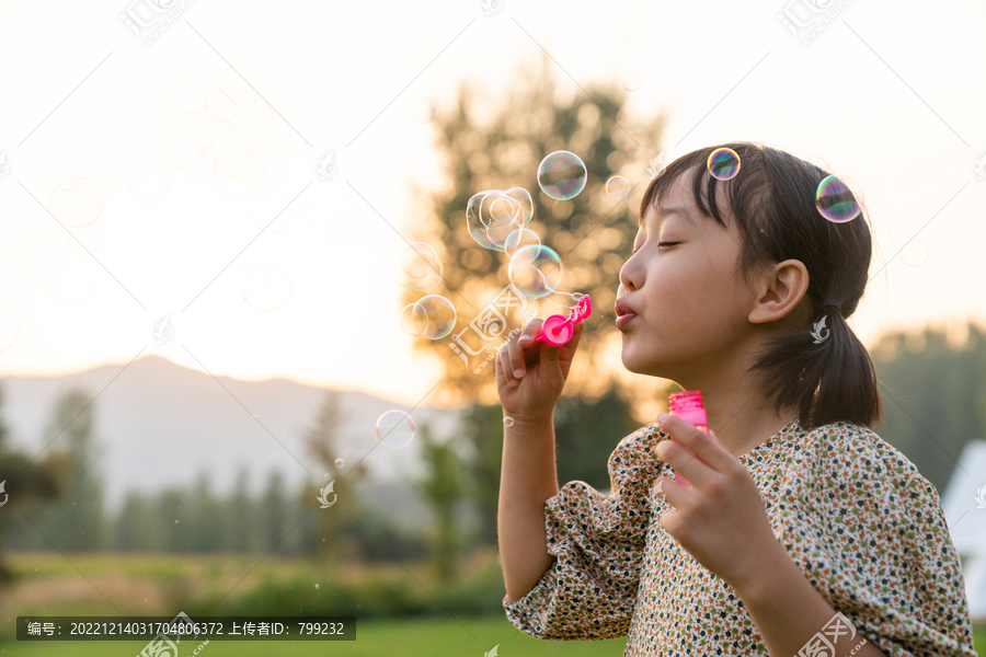 一个小女孩在草地上吹泡泡