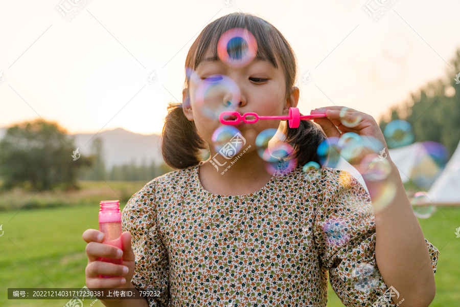 一个小女孩在草地上吹泡泡