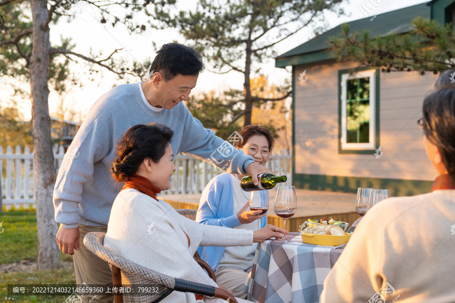 夕阳下中老年朋友在庭院里聚会喝酒聊天