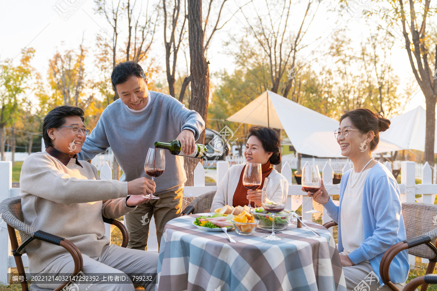 夕阳下中老年朋友在庭院里聚会喝酒聊天