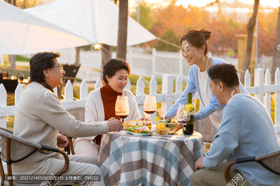 夕阳下中老年朋友在庭院里聚会喝酒聊天