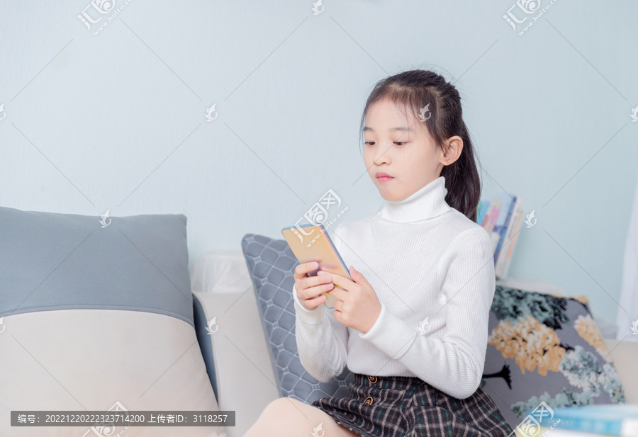 沙发上使用手机的小女孩
