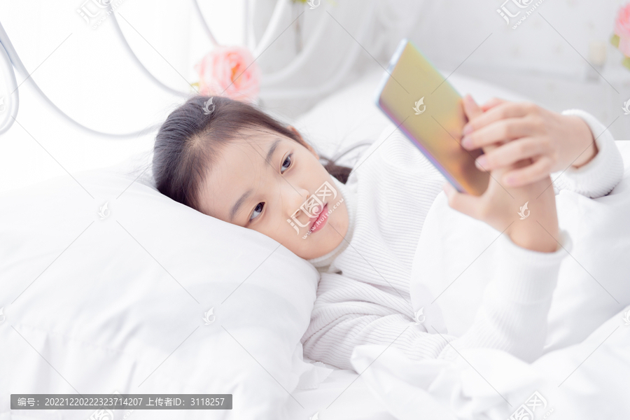 床上玩手机的小女孩