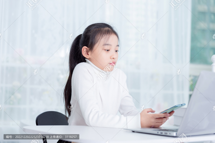 电脑前使用手机的女孩