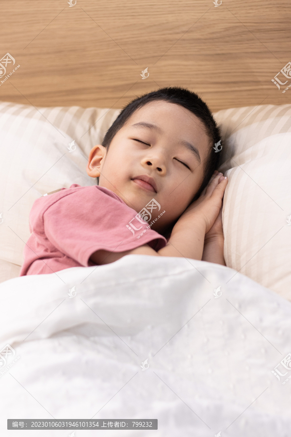 一个小男孩躺在舒适的床上睡觉