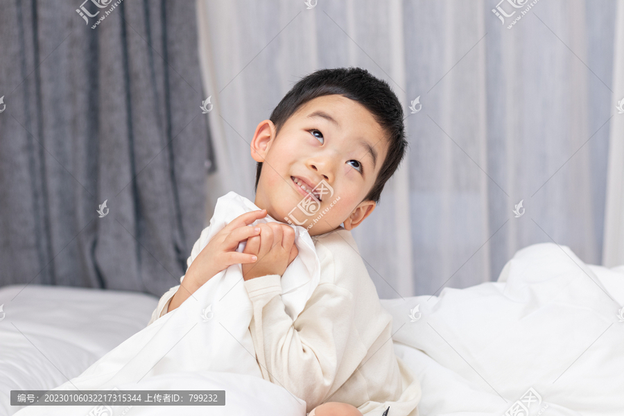 一个小男孩坐在舒适的床上开心笑