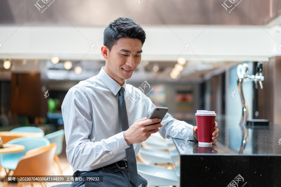 商务人士坐在吧台喝咖啡看手机