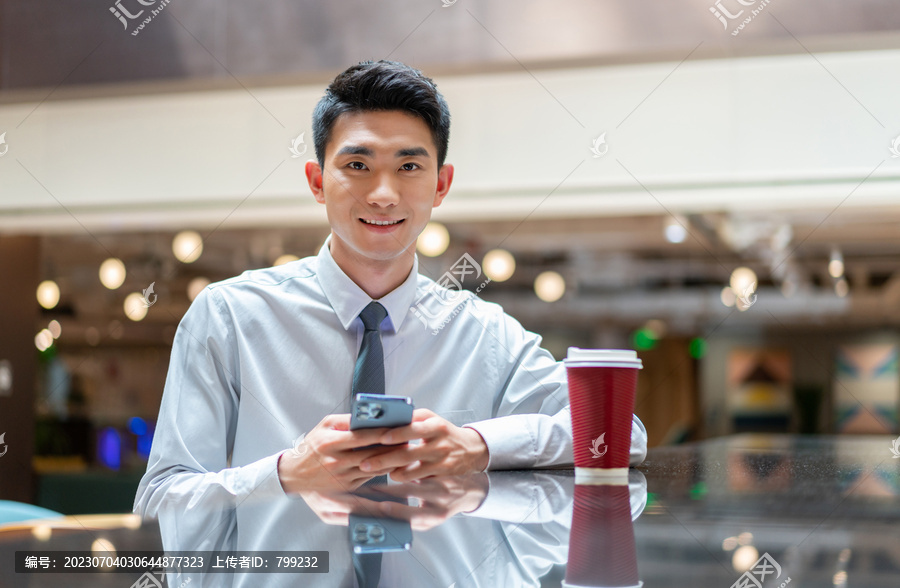 商务人士坐在吧台喝咖啡看手机
