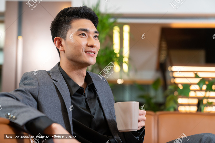 商务人士坐在沙发上喝咖啡抬头微笑