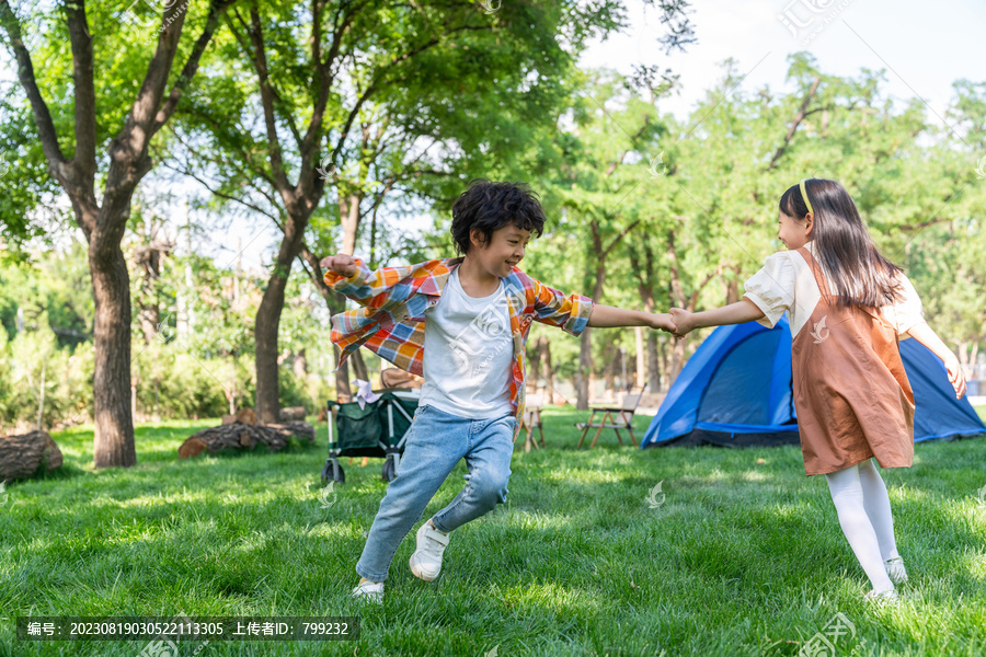 两个孩子在草地上手拉手开心转圈做游戏