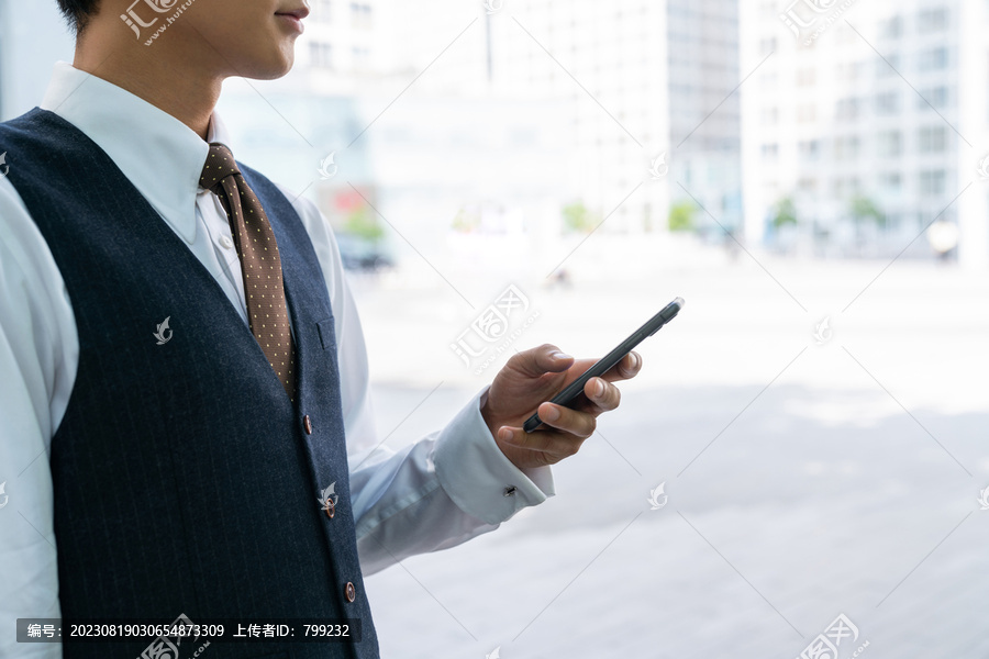 商务男士使用手机行走在写字楼群