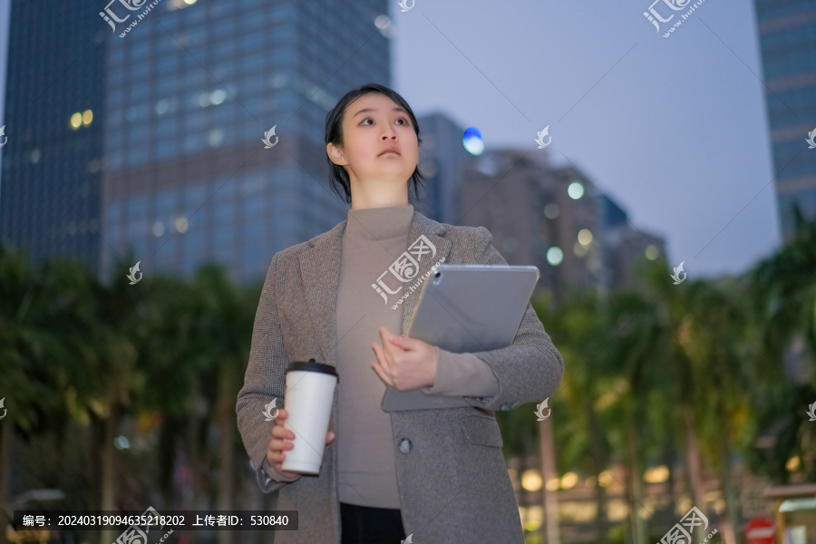 职业女性拿着电脑行走在城市夜晚