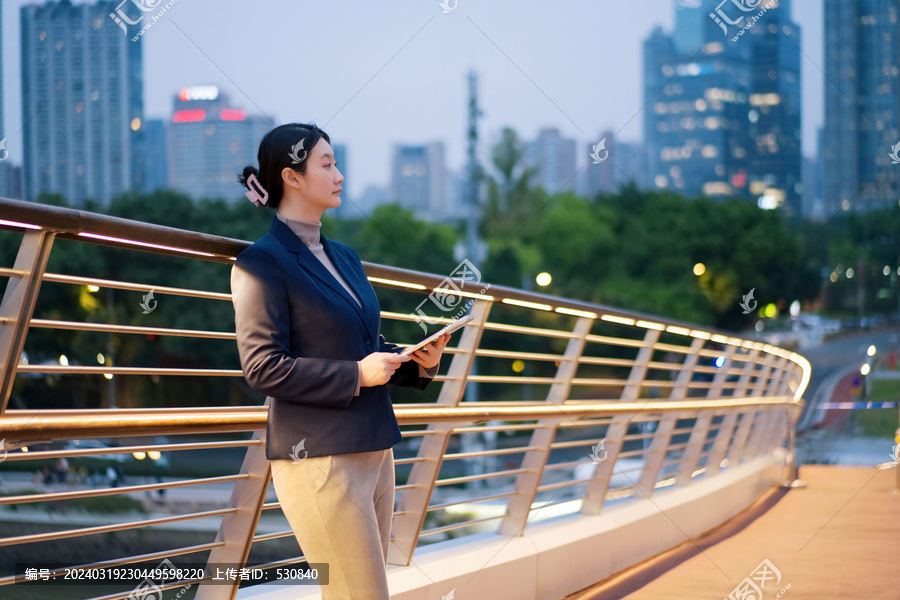 敬业女性手持平板站在城市桥上