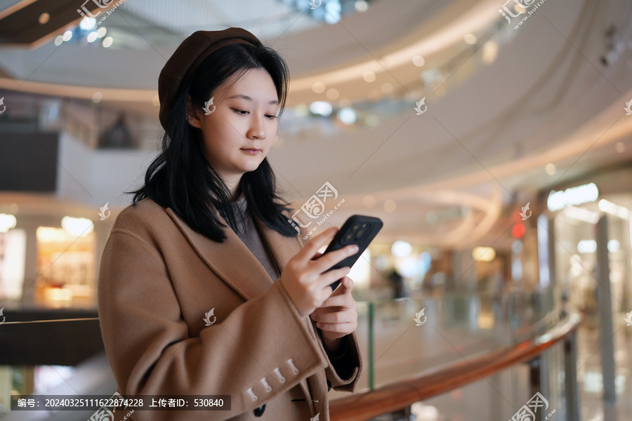 商场走廊上年轻女性查看手机
