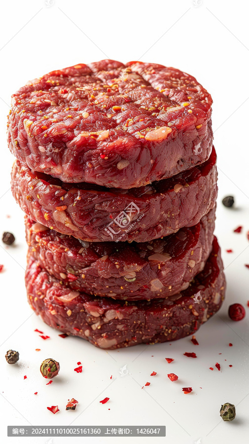 四個生的漢堡肉餅垂直堆疊周圍散落著胡椒粉