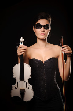 戴着黑色面具的性感女人拿着白色小提琴