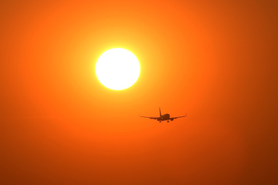 夕阳晚霞中降落的飞机