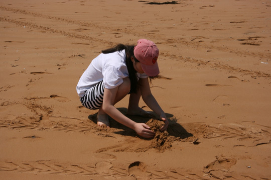 在海边沙滩堆沙玩耍的女孩