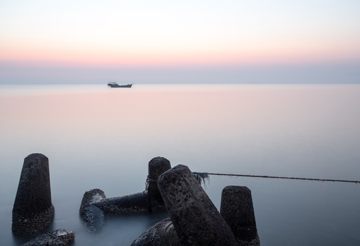 黎明前海边的礁石与渔船