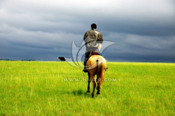 草原上男人骑马背影