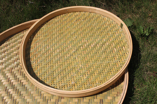 竹编做的圆形簸箕在太阳晾晒图片
