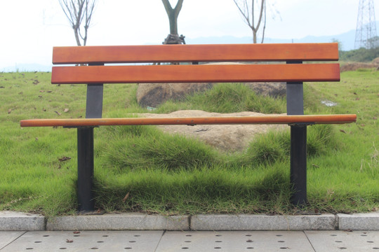 户外公园草地上红色木质长椅摄影