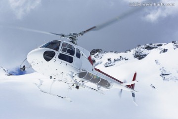 飞越雪山山峰的直升机