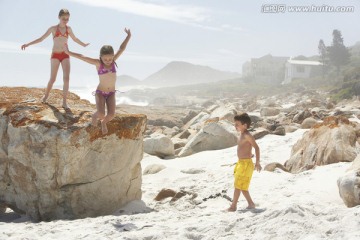 三个孩子在岩石海滩玩